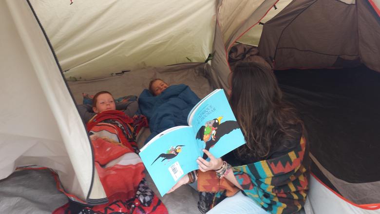 Les enfants, dans la tente et au chaud dans le duvet, écoute une histoire.